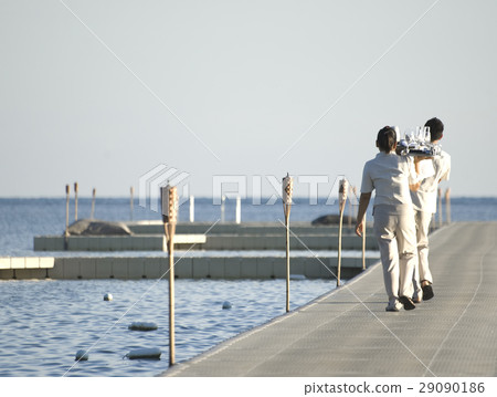 Beach waiters holding trays with glasses back view Beach waiters holding trays with glasses back view 29090186