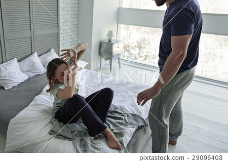 Frightened woman sitting on bed 29096408