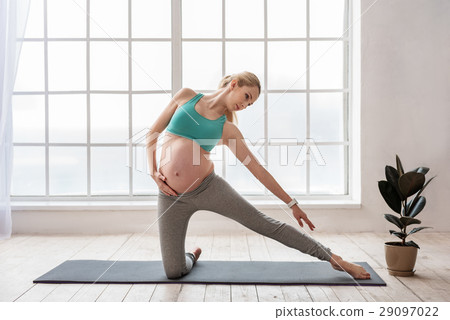 Cute expectant female in sportswear doing yoga Cute expectant female in sportswear doing yoga 29097022