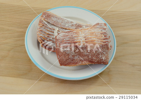 Frozen turkey bacon strips thawing on white plate 29115034