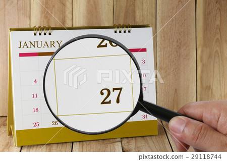 Magnifying glass in hand on calendar in January. 29118744