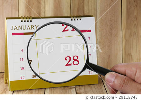 Magnifying glass in hand on calendar in January. Magnifying glass in hand on calendar in January. 29118745