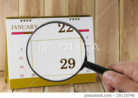 Magnifying glass in hand on calendar in January. Magnifying glass in hand on calendar in January. 29118746