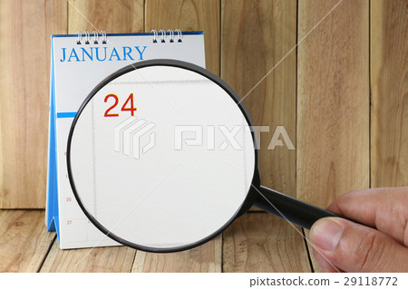 Magnifying glass in hand on calendar in January. Magnifying glass in hand on calendar in January. 29118772