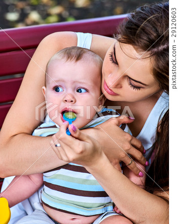 Baby feeding spoon by mother in park outdoor Baby feeding spoon by mother in park outdoor 29120603