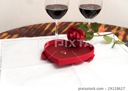 Diamond ring inside red rose over two wine glasses Diamond ring inside red rose over two wine glasses 29128627