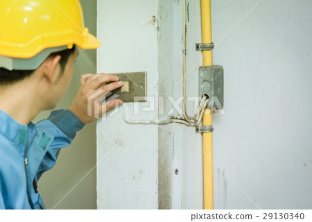 Young electrician checking switch inside building 29130340