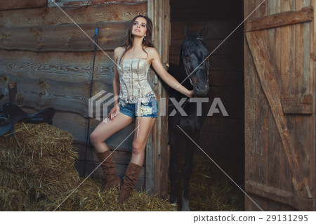 Woman holds a horse for a bridle. 29131295