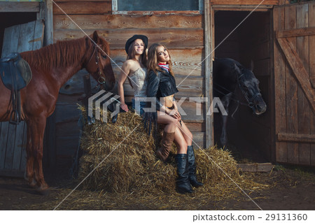 Two women are sitting on a straw on a farm. 29131360