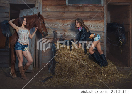 Two women are at the ranch near the stables. 29131361