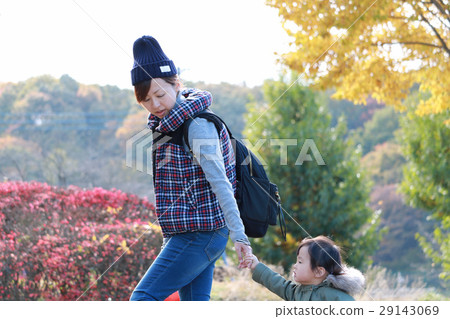 Mother and child walking in autumn leaves 29143069