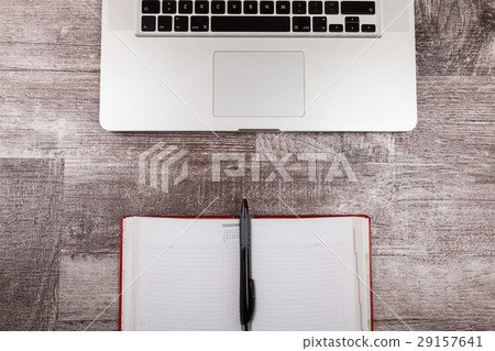Open writing notebook next to a laptop 29157641