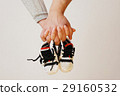 Happy young parents hold in their hands children's shoes of futu 29160532