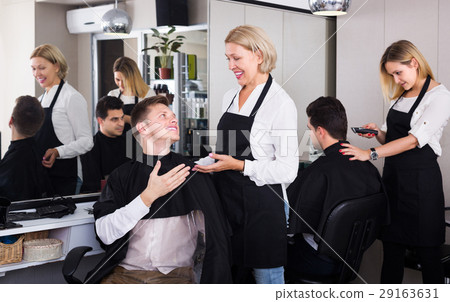 Elderly hairdresser serving teenager 29163631