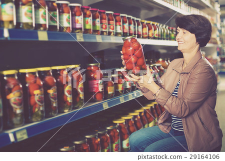 elderly woman buying canned tomatoes. 29164106
