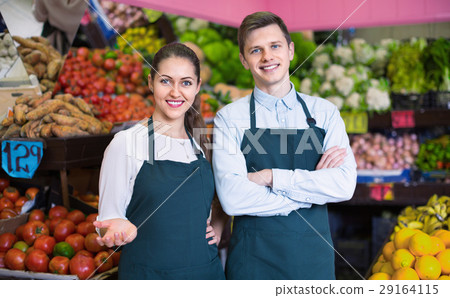 Smiling sellers having vegetables and fruits on displays Smiling sellers having vegetables and fruits on displays 29164115