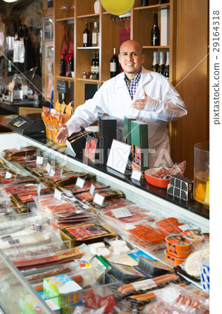 Seller at counter with jamon and wursts . 29164318