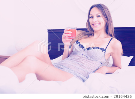 woman drinking juice in bed 29164426
