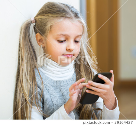 Little girl with cell phone indoors. 29164427