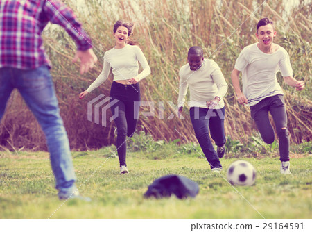 Portrait of four friends posing on countryside field with ball Portrait of four friends posing on countryside field with ball 29164591