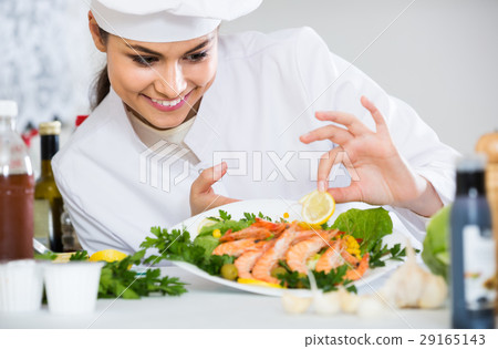 Professional female cook decorating prepared dish of shrimps 29165143
