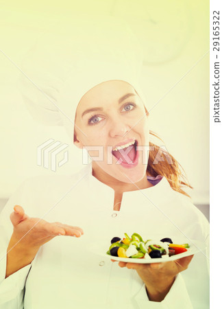 portrait of young coosie woman showing salad at kitchen 29165322