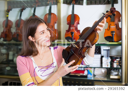 Teenage girl selecting classical violin Teenage girl selecting classical violin 29165392