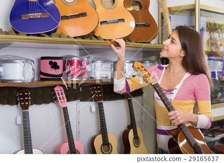 Teenage girl selecting guitar in shop. Teenage girl selecting guitar in shop. 29165637