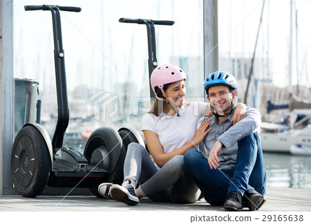 Couple sitting near segways at sea front Couple sitting near segways at sea front 29165638