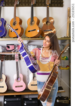 Teenage girl selecting guitar in shop. 29165651
