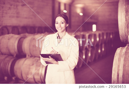 Portrait of woman holding cardboard with notes in cellar with woods Portrait of woman holding cardboard with notes in cellar with woods 29165653