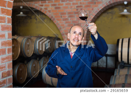 winery employee in cellar with glass of wine. 29165659