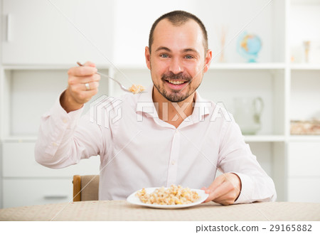 Positive young man eating porridge 29165882