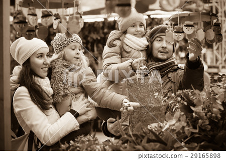 Happy smiling family of four buying Caga Tio. Focus on woman and ittle girl Happy smiling family of four buying Caga Tio. Focus on woman and ittle girl 29165898
