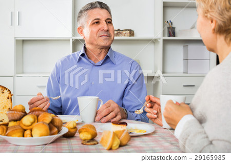 Mature couple have an afternoon snack with fresh muffins and cake Mature couple have an afternoon snack with fresh muffins and cake 29165985