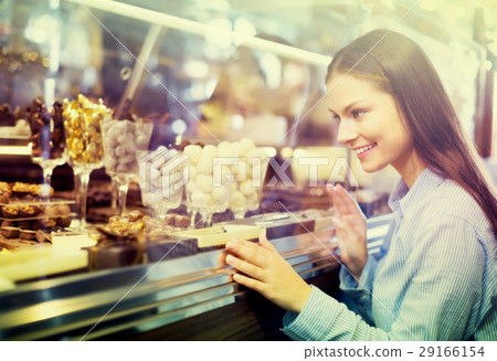 Smiling girl choosing chocolates. 29166154