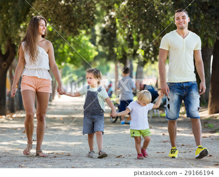 parents with two little children through park 29166194