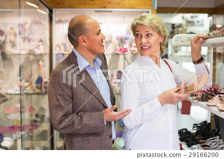 Mature couple picking shoes in boutique. Mature couple picking shoes in boutique. 29166200