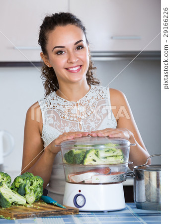 Woman steaming salmon and vegetables. 29166226