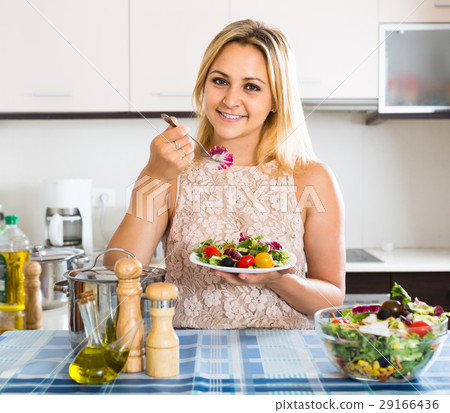girl standing at kitchen table with plate of salad 29166436
