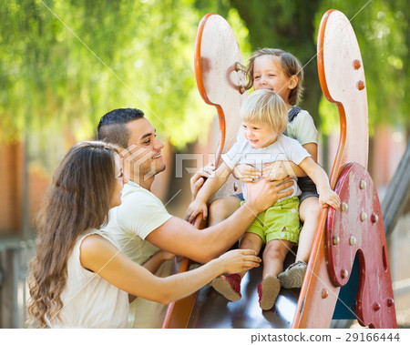 Smiling parents helping kids on slide 29166444