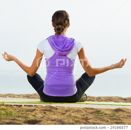 Woman doing youga training cross-legged on beach 29166877
