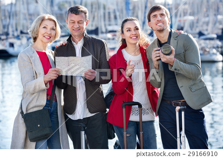 Two couples with luggage search for sights on map 29166910