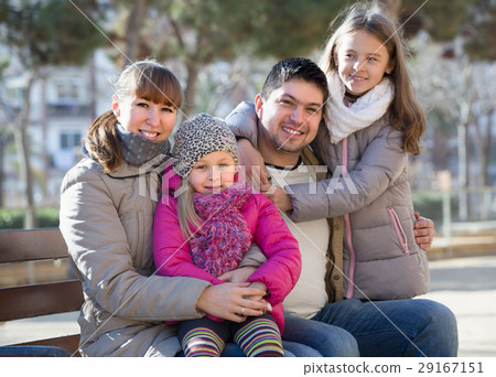 Parents with little daughters on bench. 29167151