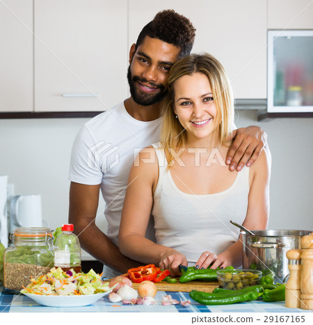 afro man and white woman cooking at kitchen table afro man and white woman cooking at kitchen table 29167165
