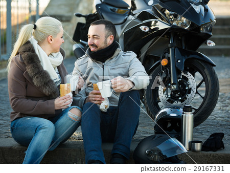 adults chatting near motorcycle 29167331