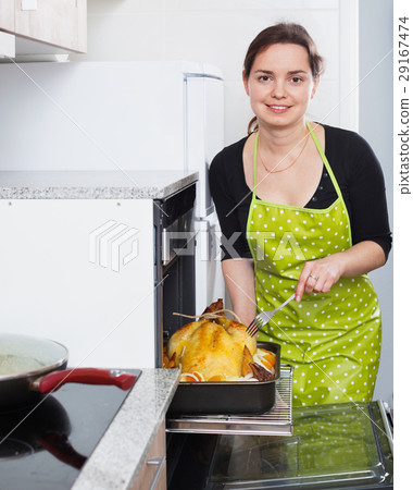 Smiling woman roasting cockerel for dinner Smiling woman roasting cockerel for dinner 29167474