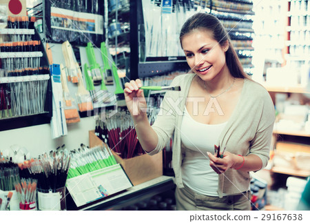 young woman selecting brushes in shop young woman selecting brushes in shop 29167638