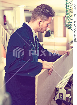Positive guy fixing chipboard on table at workshop Positive guy fixing chipboard on table at workshop 29167655