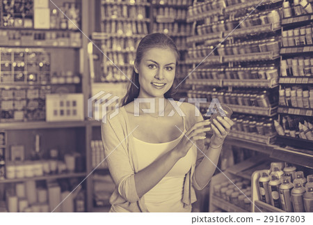 Portrait of young cheerful woman choosing paint color in jar Portrait of young cheerful woman choosing paint color in jar 29167803